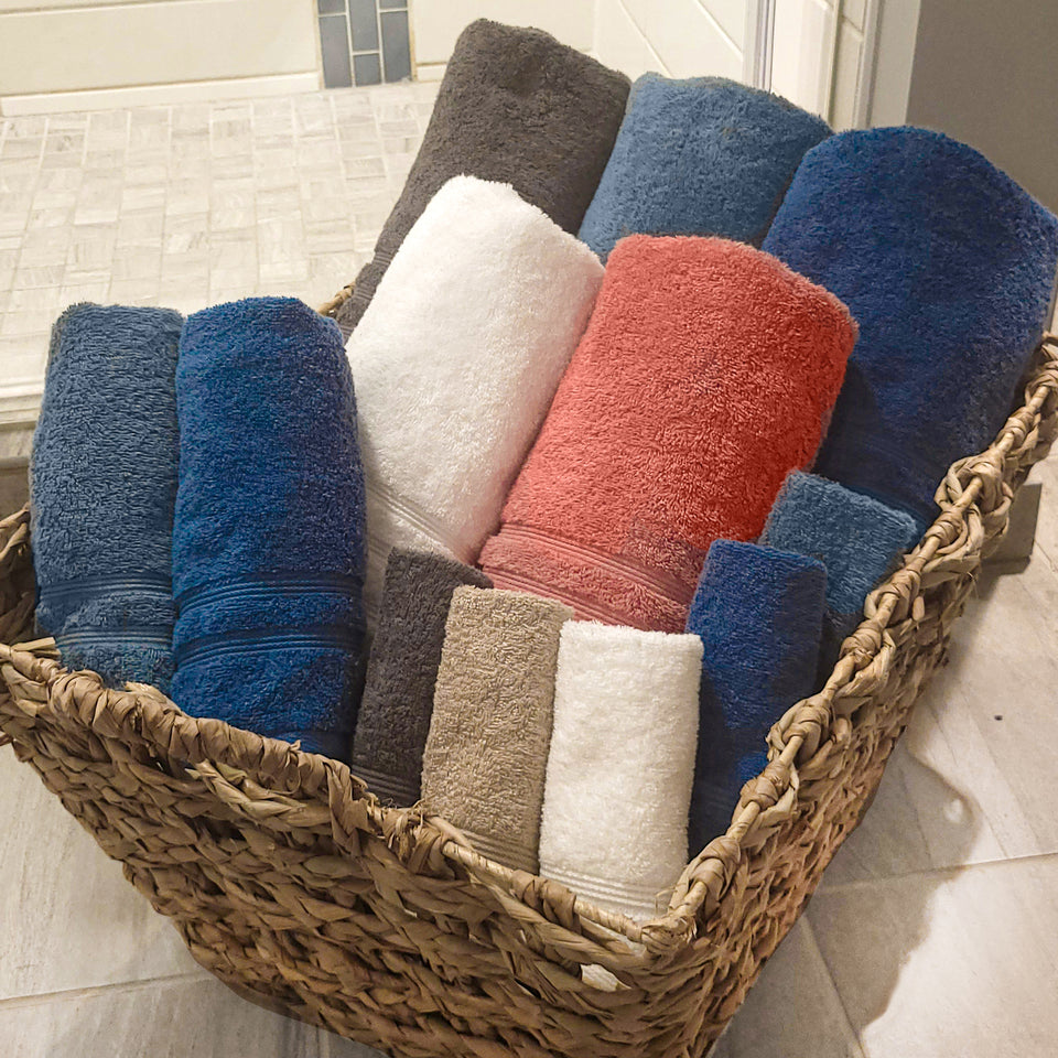 Multiple colors of American Choice Classic towels rolled and placed in a basket.