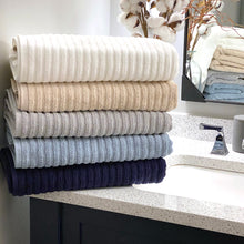 Load image into Gallery viewer, Five colors of different ribbed towel folded on a batroom sink.
