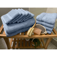 Load image into Gallery viewer, Twelve glacier blue spa collection towels folded on a table beside of a shower. 
